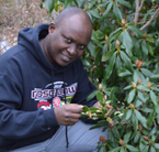 Leonard Kiirika crouching next to a rhododendron